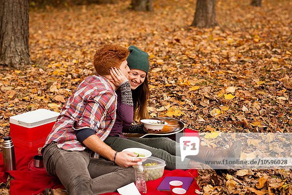 Romantic young couple having picnic in autumn forest