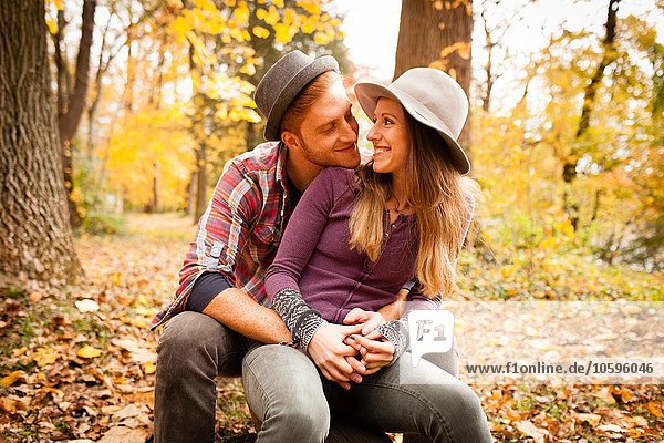 Romantic young couple sitting in autumn forest