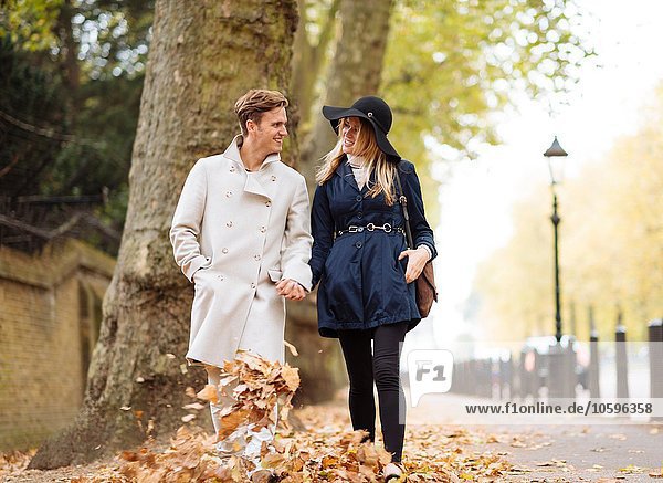 Young couple strolling through autumn leaves  London  England  UK