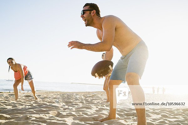 Adult friends playing American football on Newport Beach  California  USA