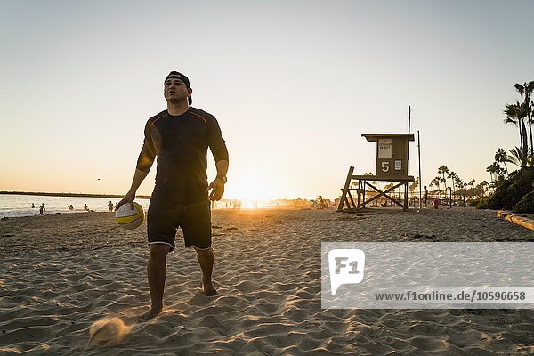 Junger Mann beim Beachvolleyball bei Sonnenuntergang  Newport Beach  Kalifornien  USA
