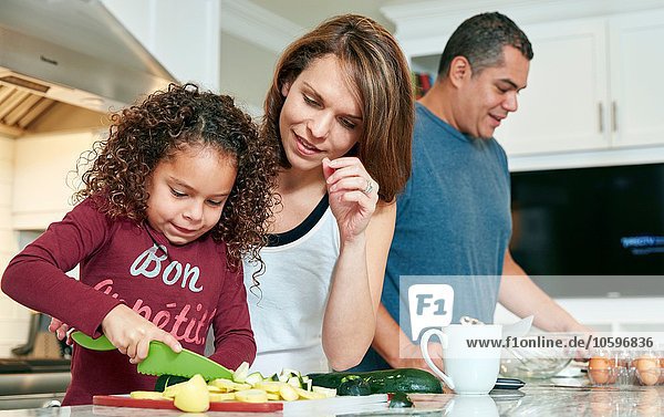 Mother helping daughter chop vegetables in kitchen