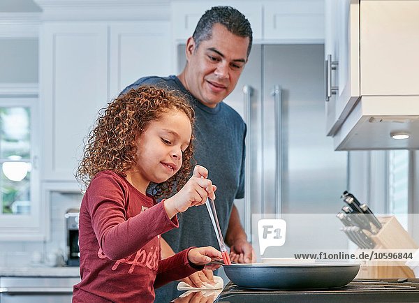 Vater hilft Tochter beim Kochen in der Küche