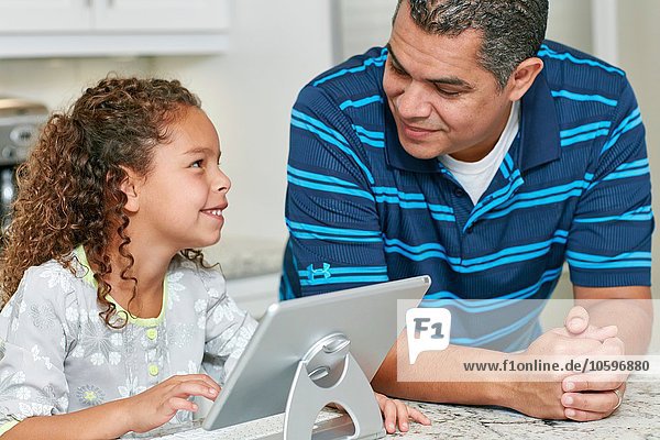 Vater und Tochter mit digitalen Tabletts von Angesicht zu Angesicht lächelnd
