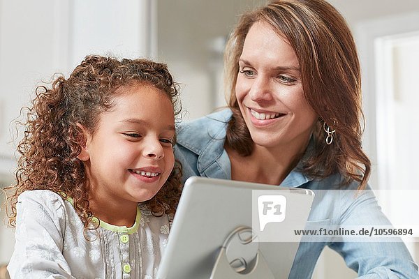 Mother and daughter using digital tablet  smiling