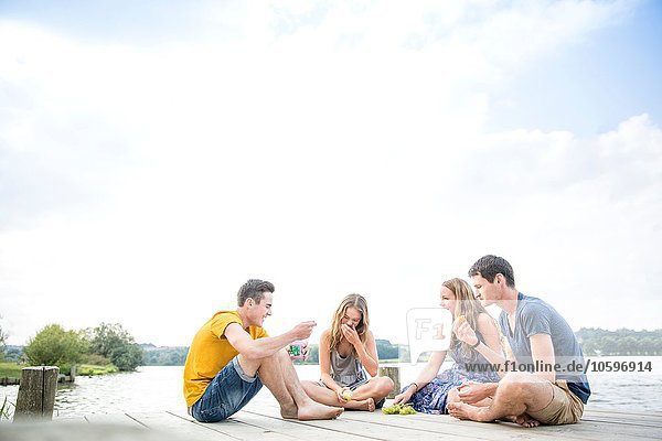 Group of young adults sitting on jetty  relaxing