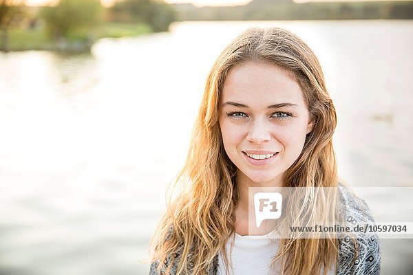 Portrait of young woman beside lake  smiling