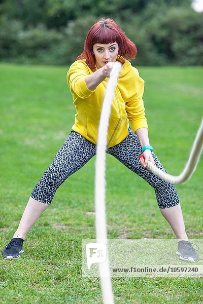 Young woman pulling rope on field