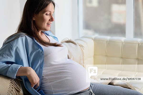 Schwangere Frau auf dem Sofa sitzend