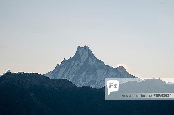 Schneebedeckter Berggipfel gegen dunkle Bergkette  Nepal