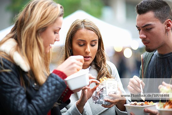Gruppe junger Erwachsener beim Essen zum Mitnehmen  im Freien