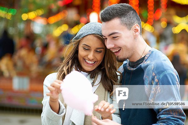 Young couple eating candy floss at funfair  outdoors
