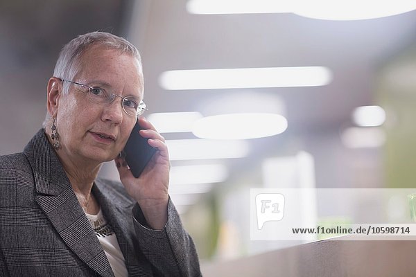 Senior Geschäftsfrau im Chat auf dem Smartphone in der Hotellobby