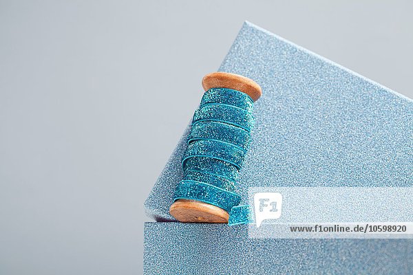 Holzrolle mit funkelndem blauen Band auf der Oberseite der Geschenkverpackung