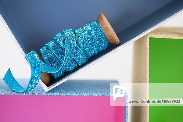 Holzrolle mit funkelndem blauen Band im Geschenkkarton
