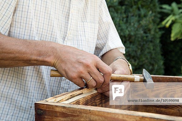Senior Mann macht Holzkiste im Garten  Mittelteil