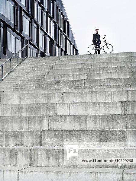 Stadtradfahrer mit Fahrrad auf der Treppe stehend