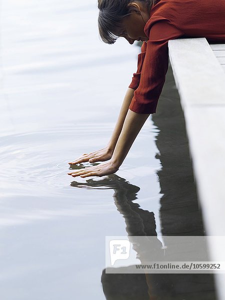 Frau auf der Vorderseite liegend am Pier hängend  Wasseroberfläche berührend  Kopenhagen  Dänemark