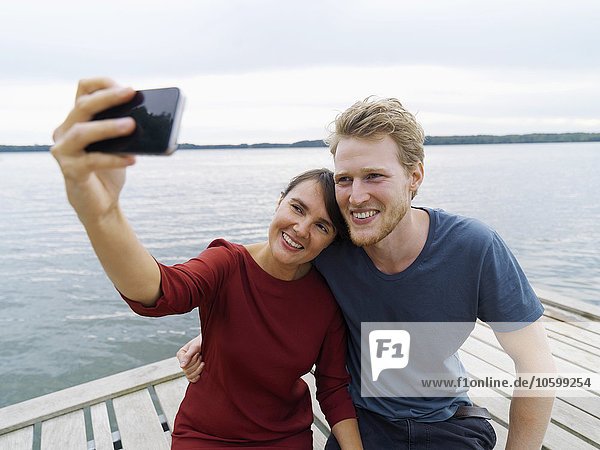 Pärchen am Pier Seite an Seite mit dem Smartphone  Kopenhagen  Dänemark