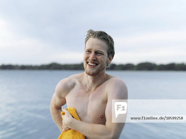 Nackter junger Mann  der mit einem Handtuch abtrocknet  lächelnd wegschaut  Kopenhagen  Dänemark