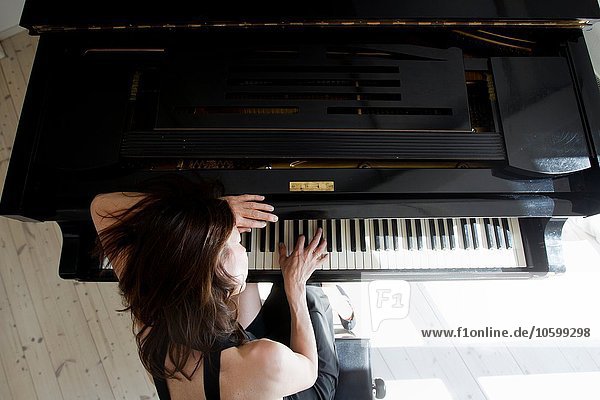Overhead-Ansicht einer reifen Frau  die sich auf das Klavierspiel stützt.