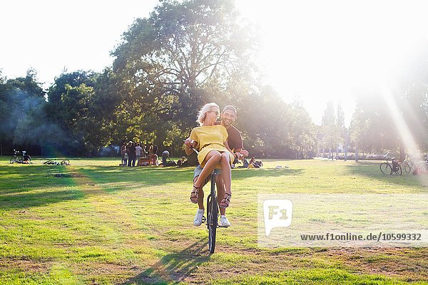 Junges Paar bei Sonnenuntergangsparty im Park auf dem Fahrrad