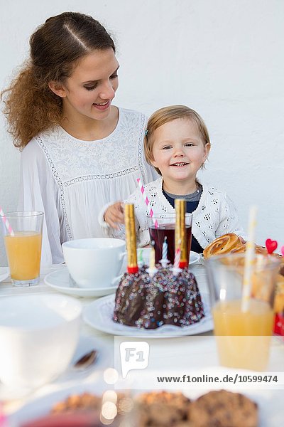 Teenage girl and toddler at patio table for birthday party