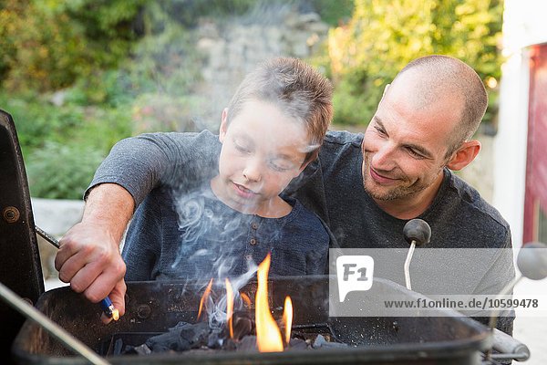 Mittlerer Erwachsener Mann und Sohn beim Grillen im Garten