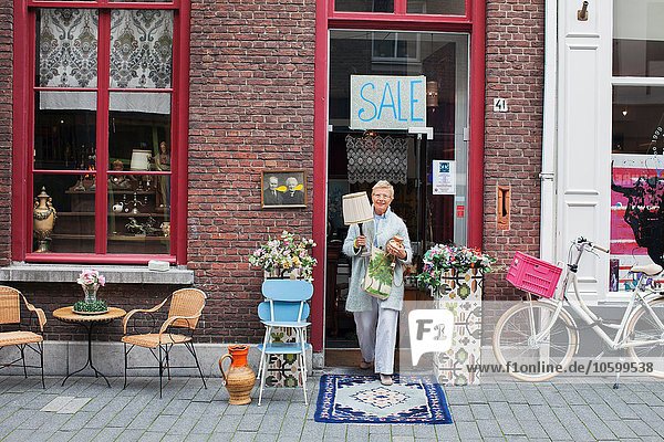 Reife Kundin mit Lampe vor dem Vintage-Shop