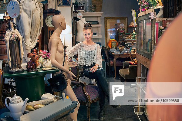 Portrait of stylish young woman sitting in vintage shop