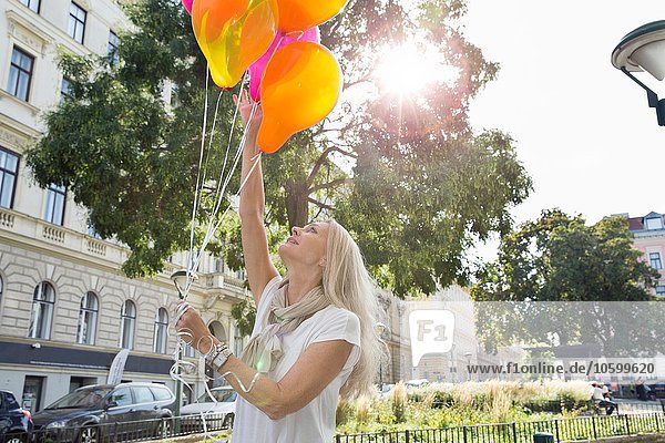Reife Frau  im Freien  hält einen Haufen Ballons in der Hand