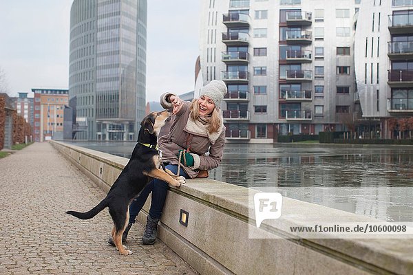 Mittlere erwachsene Frau füttert ihre Hundesnacks an der Uferpromenade