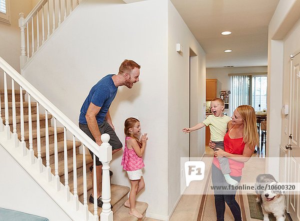 Family playing peek-a-boo on staircase at home