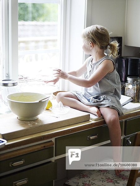 Skandinavien  Schweden  Mädchen bereitet Essen in der Küche vor  schaut aus dem Fenster