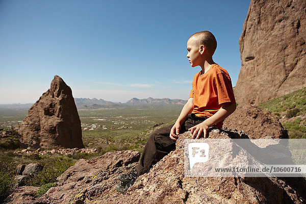 Boy sitting on rock in desert landscape