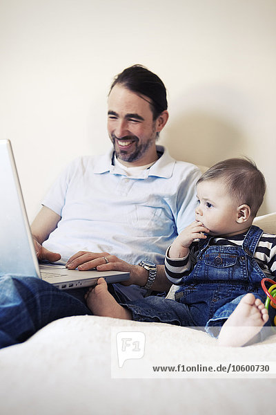 Man using laptop with baby next to him