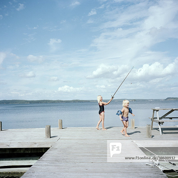 Boy and girl playing on jetty