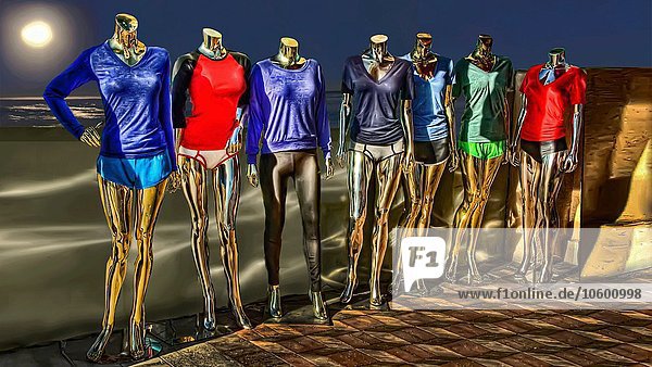 Weibliche Schaufensterpuppen mit bunten Kleidern am Strand bei Nacht