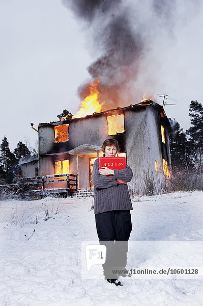 Gerettete Seniorin vor brennendem Haus mit Fotoalbum