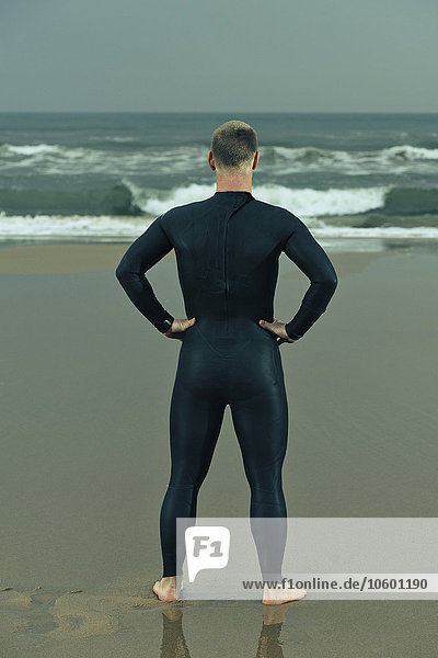 Man wearing wetsuit and standing on beach