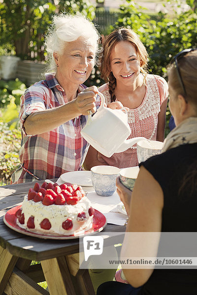 Vier Frauen genießen Kuchen und Tee im Garten