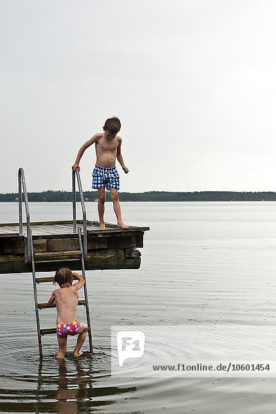 Two boys on jetty by sea