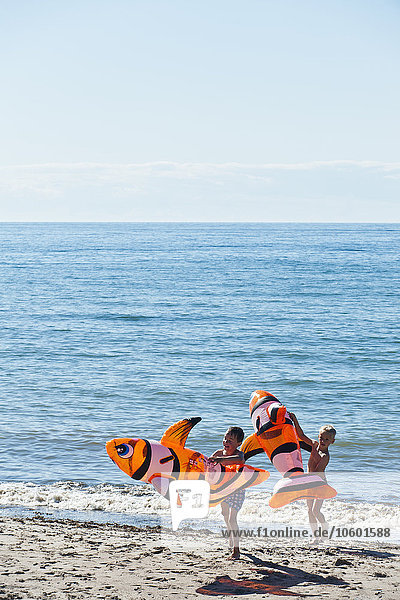 Jungen am Strand mit aufblasbarem Spielzeug