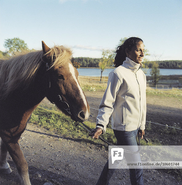 Eine Frau  die mit einem Pferd spazieren geht.