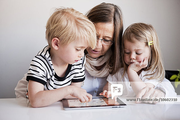 Grandmother with grandchildren using digital tablet