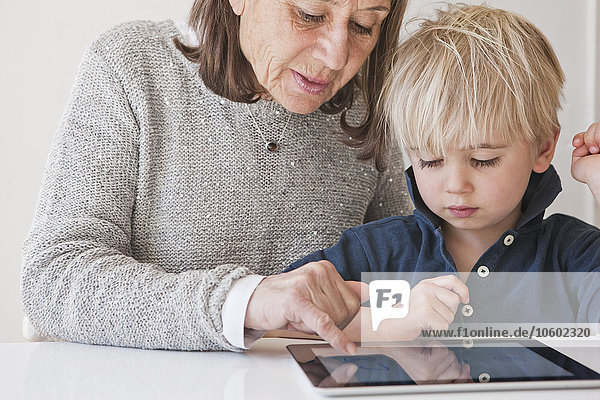 Großmutter mit Enkel  der ein digitales Tablet benutzt