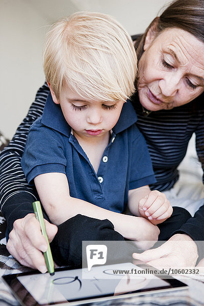 Großmutter und Enkel benutzen ein digitales Tablet
