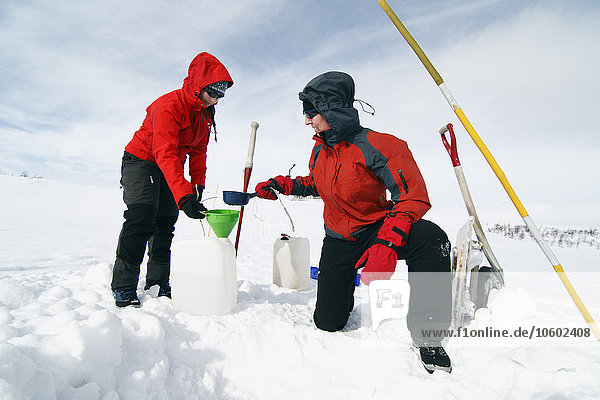Women taking water from frozen lake  Ammarnas  Lapland  Sweden