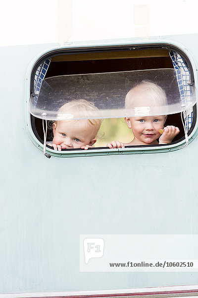 Zwei Kinder schauen durch das Fenster eines Wohnwagens  Jarvso  Schweden