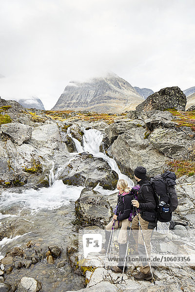 Couple in mountains looking at stream